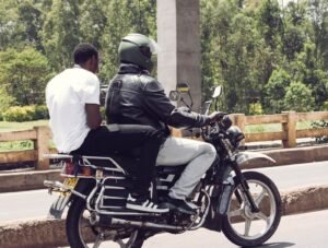 Two men on a motorcycle taxi riding through a Nairobi street, Kenya