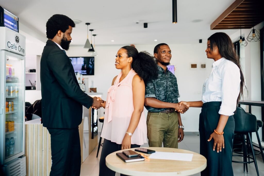 Four young professionals shaking hands in a café in Lagos, Nigeria
