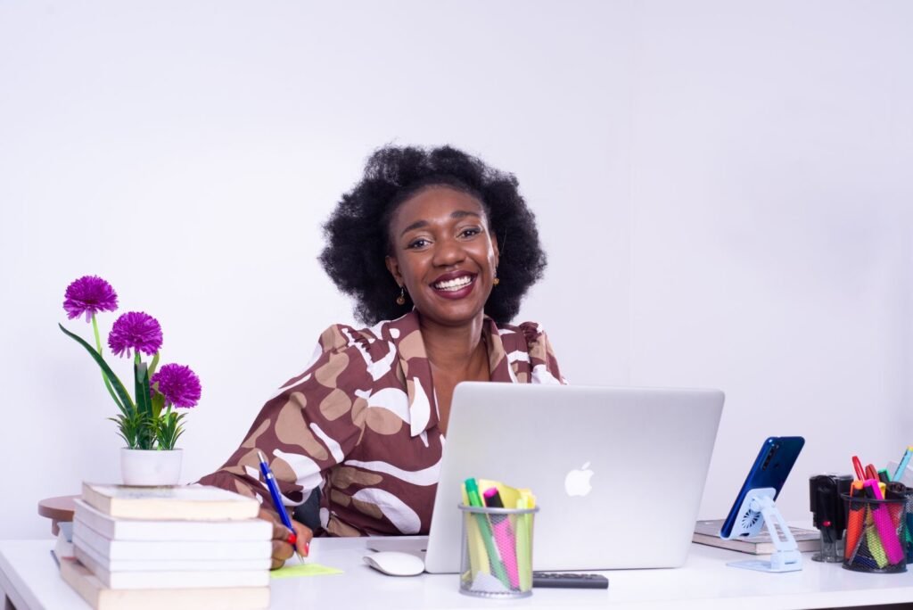 A smiling founder at her desk with a laptop and phone in Kinshasa, DR Congo