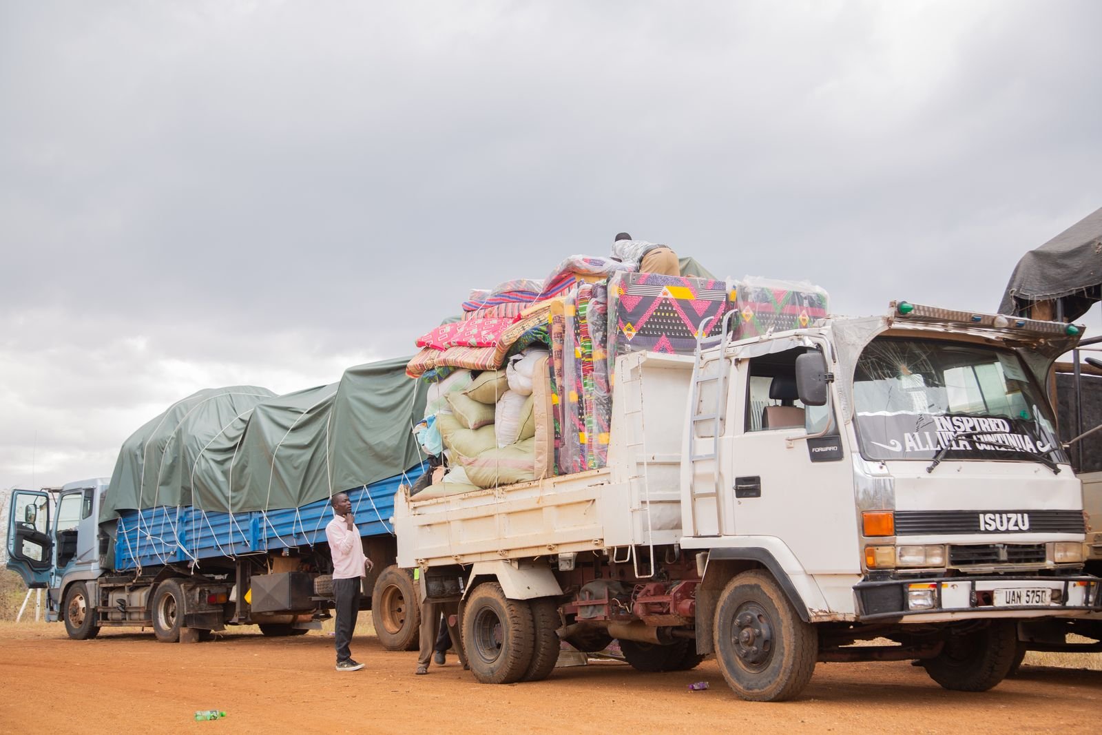 Trucks loaded with goods parked on a dirt road in rural Uganda
