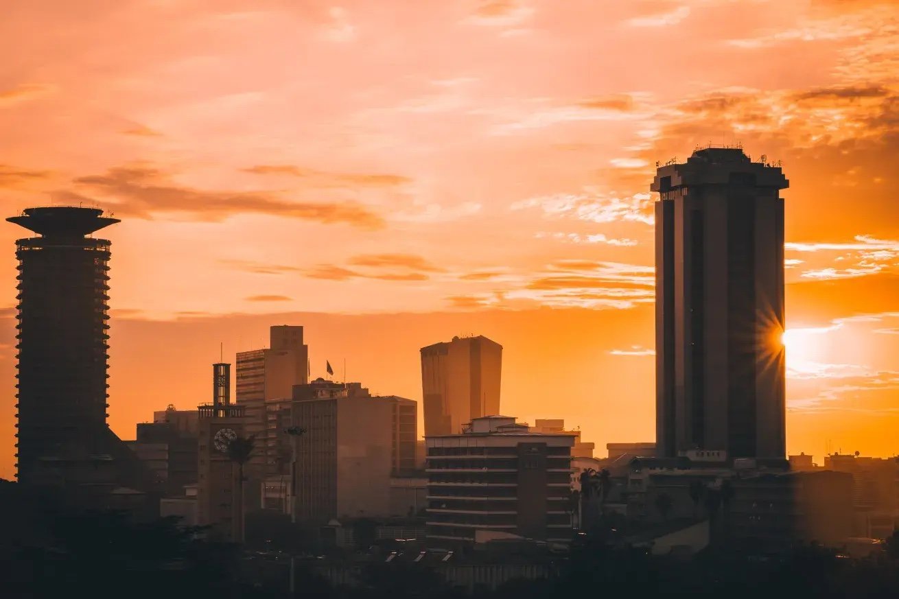 Nairobi skyline silhouetted against an orange sunset, with the KICC tower on the left