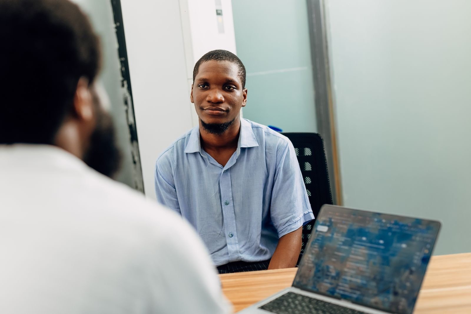 Two professionals in a one-to-one conversation across a desk in a Lagos office