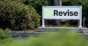 Revise sign with the lime arrow logo outside an office, surrounded by greenery