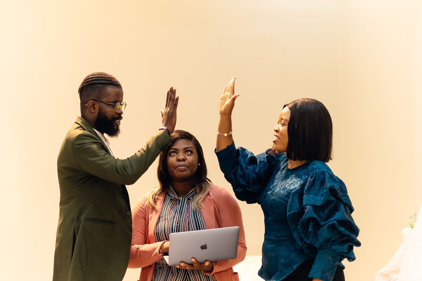 Three colleagues celebrating with a high five in an office in Lagos, Nigeria